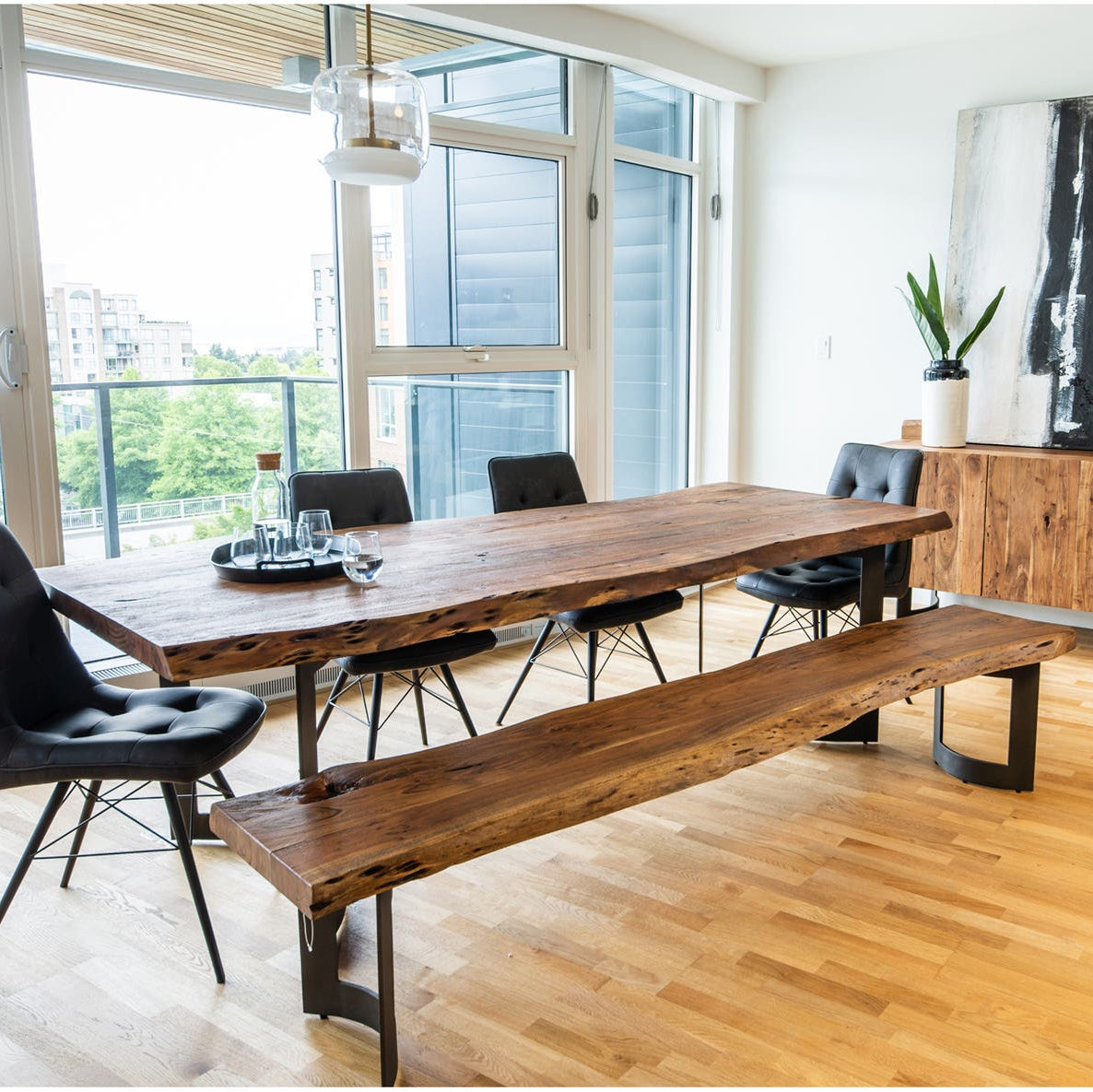 Modern dining area with a long wooden table and chairs in a well-lit room.