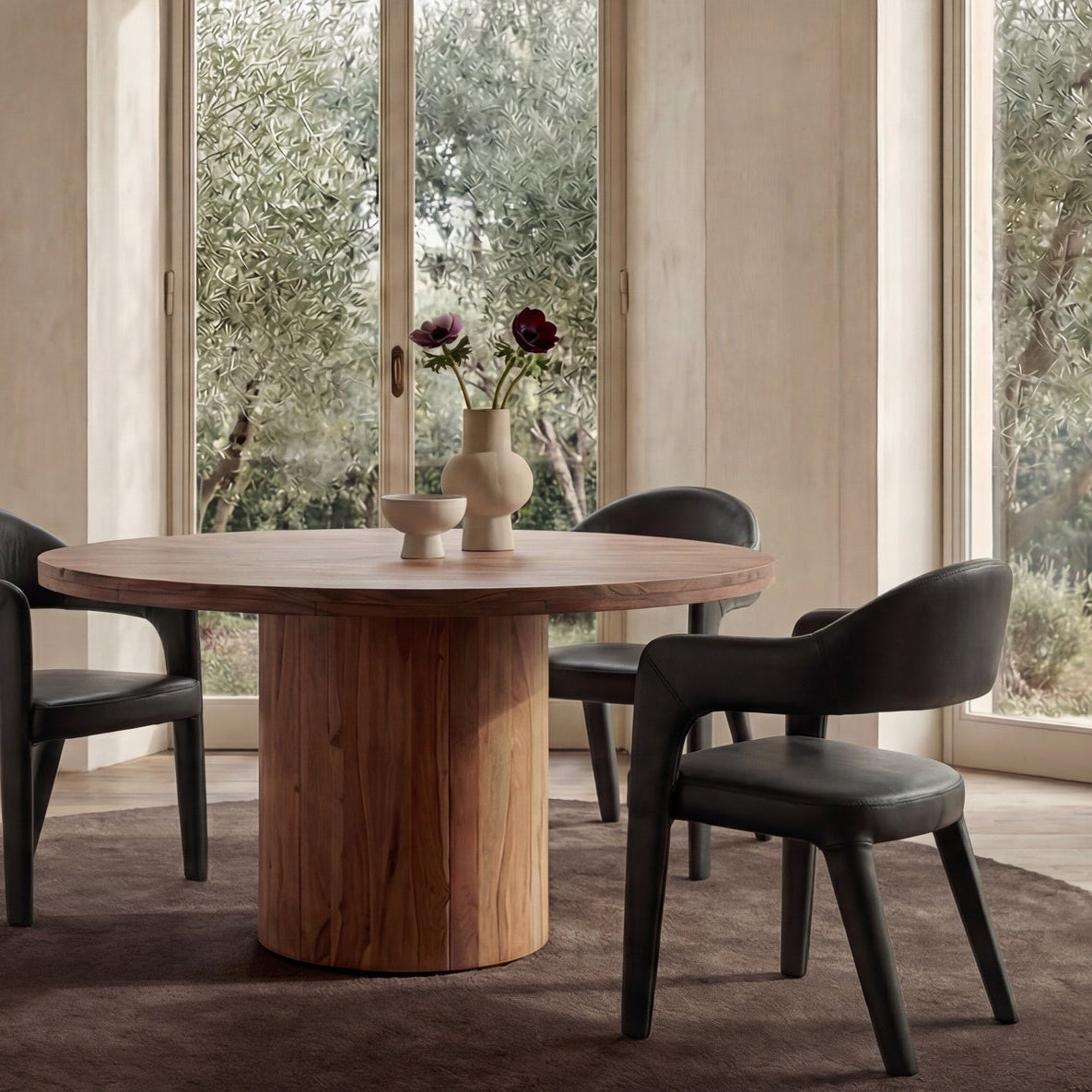 Dining area with a wooden table and black chairs in a room with large windows.