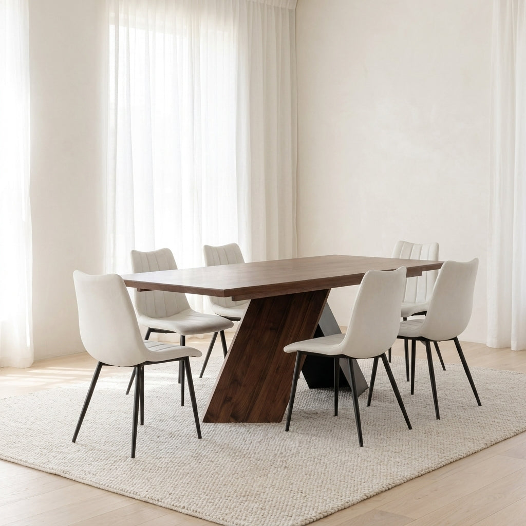 A modern dining table set in a bright, minimalist room. The set includes a rectangular dark wood dining table with a sculptural angled pedestal base, surrounded by six white upholstered dining chairs with slim black metal legs, all arranged on a textured cream-colored area rug.