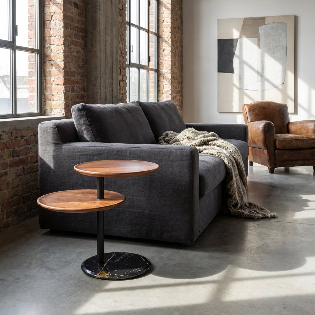 Gray sofa with a wooden side table in a modern living room with brick walls and large windows.