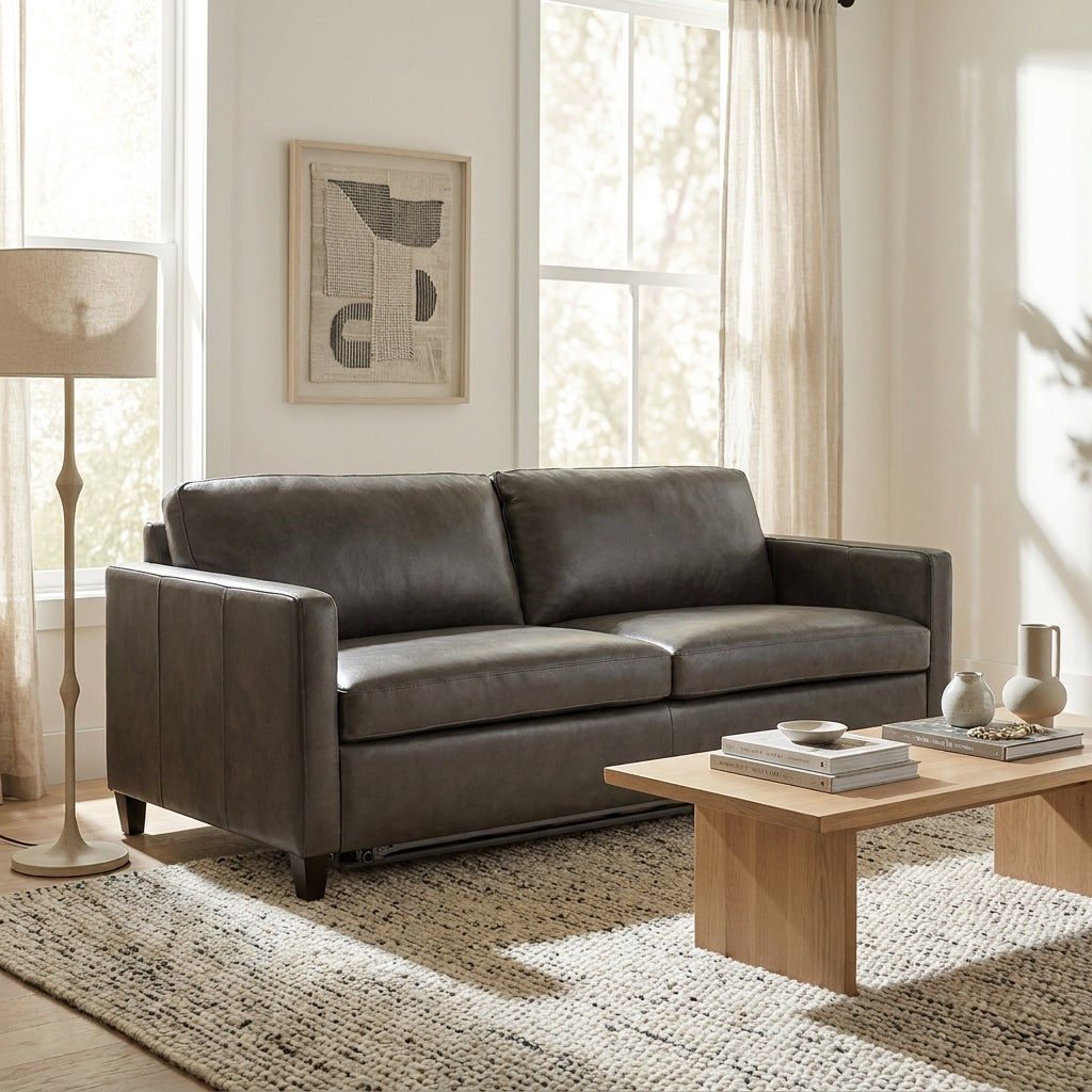 A dark brown leather loveseat sofa in a bright, modern living room setting with a wooden coffee table, textured rug, and a floor lamp.