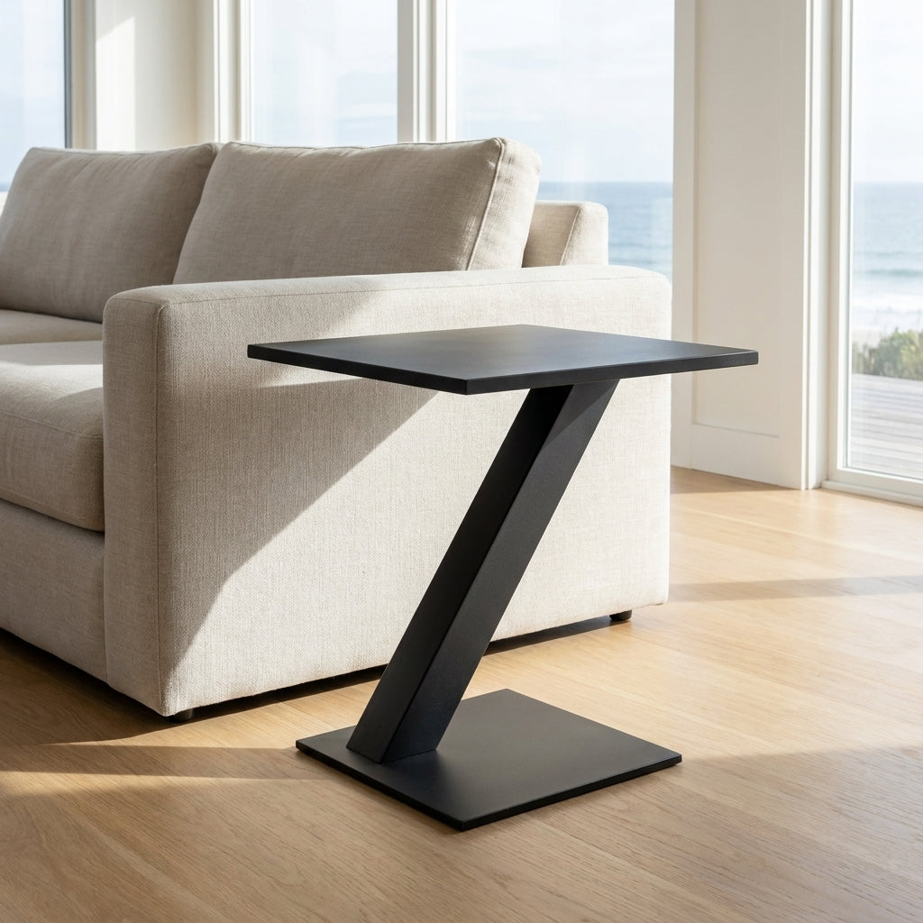 Black side table in front of a beige sofa with large windows in the background