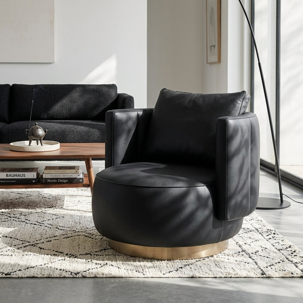 Modern black leather armchair in a living room setting with a sofa and coffee table.