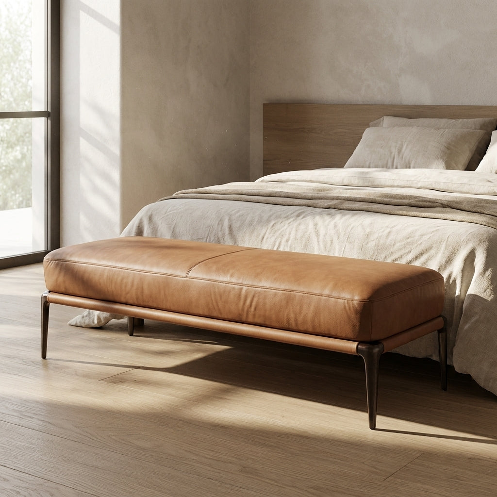 Brown leather bench in front of a bed with neutral bedding in a modern bedroom.