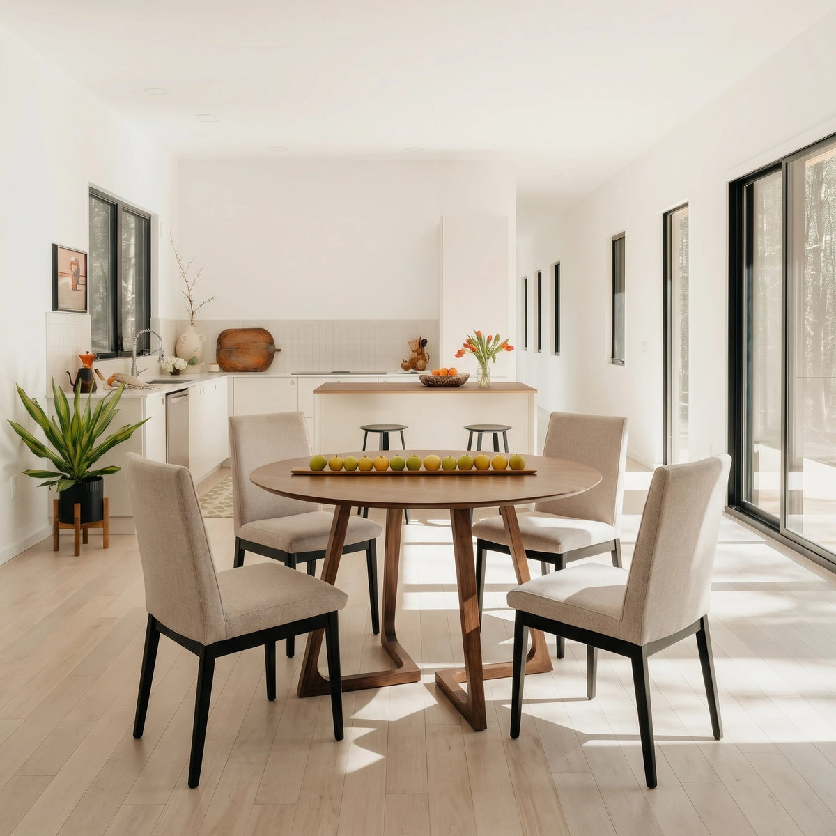 Gisborne Round Dining Table in Walnut with 4 Cole beige dining chairs in a bright open-plan room