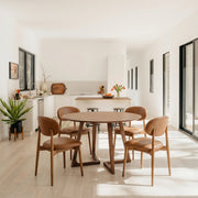 Gisborne Round Dining Table in Walnut with 4 Etta leather dining chairs in a bright open-plan room